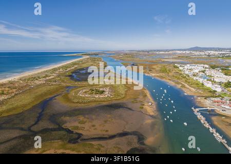 Luftbild der Küstenlandschaft und Feuchtgebiete von Ria Formosa mit kleinen Booten, die im Kanal in der Nähe der Stadt Cabanas, Faro, Portugal, vor Anker liegen. Stockfoto