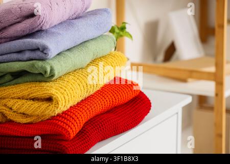 Ein Stapel bunter Strickpullover auf der Kommode im Zimmer Stockfoto