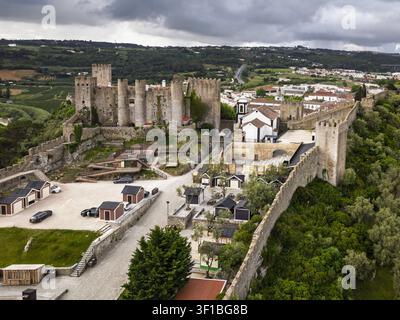 Luftaufnahme des historischen Schlosses Obidos mit seinen mittelalterlichen Steinmauern und Türmen, umgeben von üppiger Vegetation und der Stadt Obidos, Bezirk Leiria Stockfoto