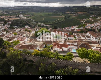 Luftbild der historischen Stadt Obidos mit ihren mittelalterlichen Mauern, Terrazzendächern und der umgebenden grünen Landschaft in Obidos, Bezirk Leiria, P Stockfoto