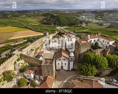 Luftaufnahme der historischen Burg und der mittelalterlichen ummauerten Stadt Obidos mit ihren Steinbefestigungen, der Kirche und der umgebenden grünen Landschaft in Obidos Stockfoto