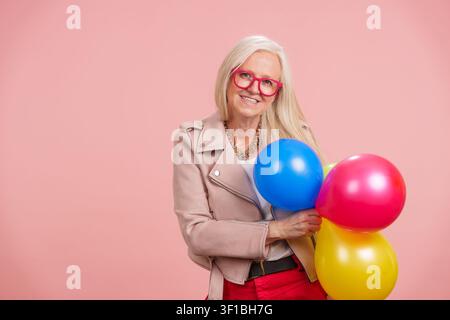 Seniorin feiert lebhaftes Altern und hält Ballons Stockfoto