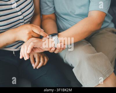 Nahaufnahme einer asiatischen Frau, die zu Hause ihre Smartwatch am Handgelenk überprüft, Konzept des Gesundheits-Trackings, tragbare Technologie, Fitnessmonitor, digitale Gesundheitsversorgung, ein Stockfoto