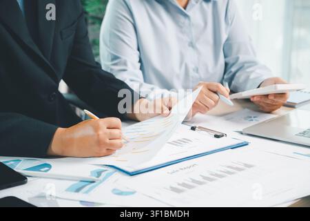 Geschäftspartner diskutieren Verkaufsbericht mit Digitaltablet, Laptop und Finanzdiagrammen im modernen Büro, was Teamarbeit in Unternehmen und Finanzen repräsentiert Stockfoto
