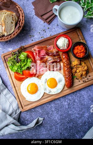 Frühstücksteller mit Spiegeleiern, Schinkenspeck und gegrillter Wurst Stockfoto