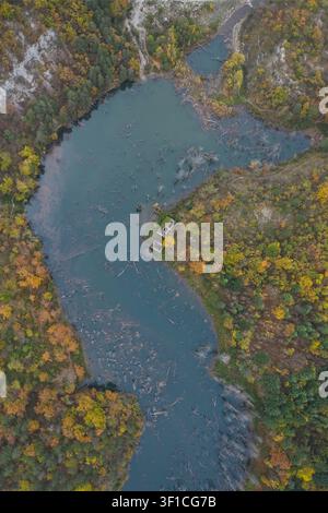 Luftbild des Lago di Poggio Baldi, umgeben von dichtem Herbstwald mit farbenfrohem Laub und im Wasser versunkenen Baumstämmen in Santa Sofia, Emi Stockfoto
