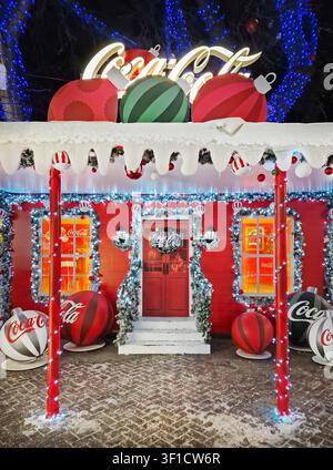 Chișinău, Moldawien - 10. Januar 2026: Ein festlich mit Coca-Cola-Motto verziertes Haus, hell für Weihnachten dekoriert mit riesigen Christbaumkugeln, schneebedeckten Dachrinnen und leuchtenden L Stockfoto