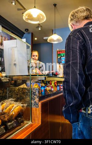 Epsom, London UK, 12. Juli 2026, Ein Mann steht mit dem Rücken zur Kamera und wartet in der Schlange, um im Caffe Nero Coffee Shop Morgenkaffee zu kaufen Stockfoto
