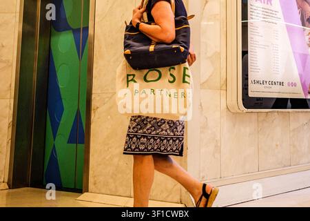 Epsom, London UK, 12. Juli 2026, Seitansicht-Körperaufnahme einer nicht erkennbaren Frau, die allein mit einer Waitrose- und einer persönlichen Schulterhandtasche geht Stockfoto