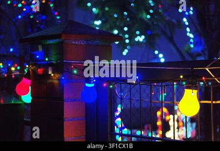 Eine atemberaubende Balkonszene im Freien, beleuchtet von lebendigen blauen und roten Weihnachtslichtern, die von unten eine festliche Atmosphäre schaffen, während man nach oben in die Wärme schaut Stockfoto