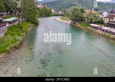 Panoramatische Ansicht des türkisfarbenen Neretva-Flusses, der sich durch eine historische Stadt schlängelt, mit üppiger Vegetation und malerischen Flussufer-Restaurants. Stockfoto
