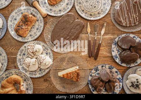 Ansicht von oben über eine Auswahl an Gebäck, darunter schokoladenüberzogene Kuchen, weiß glasierte Baiser, ein Stück Schichttorte und ein mit Streuseln überzogener Rollkuchen Stockfoto