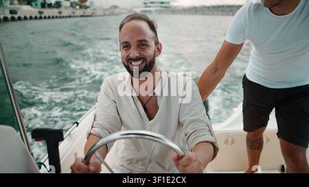 Bärtiger Mann am Steuerrad eines Bootes, der einen Sommerurlaub auf dem Wasser genießt Stockfoto