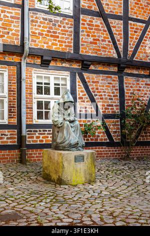 Bronze-Statue eines Kapuzenmönchs vor einem traditionellen Fachwerkhaus in Stade, Deutschland, historisches Wahrzeichen der Altstadt Stockfoto