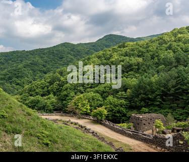 Üppige grüne Berglandschaft mit Steinmauern und ländlichem Pfad Stockfoto