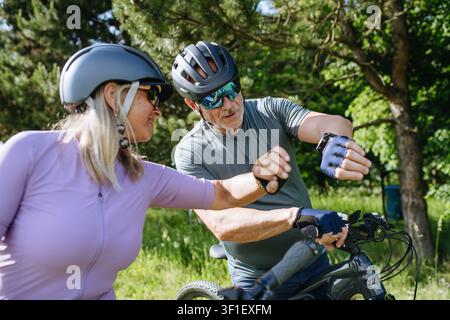 Ältere Biker machen eine Pause während einer Motorradtour und überprüfen ihre Leistung auf der Smartwatch. Stockfoto