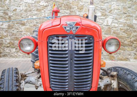 Castellgali - Spanien - 5. Mai 2026: Vorderer Nahaufnahme eines roten Vintage-Traktors mit klassischem Metalllogo, altem Agrarfahrzeuggrill, runden Scheinwerfern Stockfoto