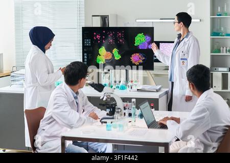 Verschiedene Wissenschaftler überprüfen Zellbilddaten in einem medizinischen Labor Stockfoto