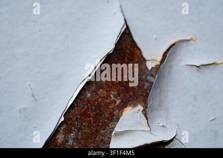 Nahaufnahme von abblätternder Farbe auf einer alten Metalloberfläche. Verwitterte Grunge-Textur mit rissiger Beschichtung, abgenutzten Details und zerstörtem Hintergrund für Designpr Stockfoto