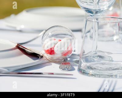Elegante formelle Tischdekoration mit Glasgeschirr, weißen Tellern und Gastgeschenken bei einer Empfangsparty Stockfoto
