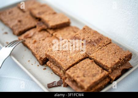 Schale mit hausgemachtem Nusskuchen, in quadratische Stücke geschnitten, auf weißem Teller, Nahaufnahme des Desserts auf dem Partybuffet. Stockfoto