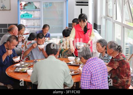 Peking, Chinas Provinz Anhui. 12. Juli 2026. Ein Freiwilliger serviert Mittagessen für umgesiedelte Menschen in einer Notunterkunft im Dorf Yanggan der Stadt Huangshan im Osten der Provinz Anhui, China, am 12. Juli 2026. Da extremes Wetter in den letzten Tagen mehrere Regionen in China getroffen hat, haben die örtlichen Behörden Katastrophenschutz- und Hilfsmaßnahmen durchgeführt, um das Leben und Eigentum der Menschen zu schützen. Credit: Fan Chengzhu/Xinhua/Alamy Live News Stockfoto
