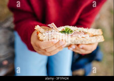 Nahaufnahme eines Kindes, das ein hausgemachtes Sandwich mit frischer Füllung hält Stockfoto