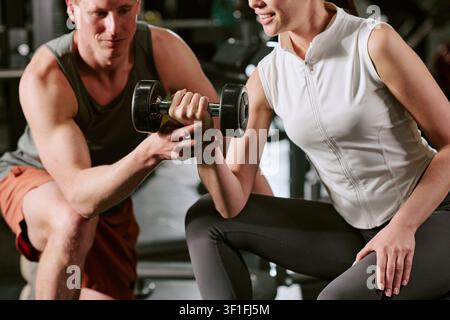 Frau trainiert mit Personal Trainer während des Fitnessstudio-Workouts Stockfoto