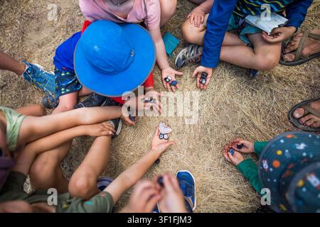 Gruppe von Kindern, die draußen sitzen und Steine teilen Stockfoto