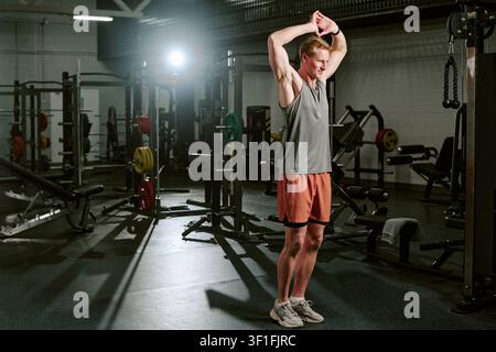 Athletischer Mann, der sich vor der Krafttrainingseinheit im Fitnessstudio aufwärmt Stockfoto