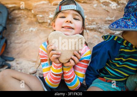 Glückliches Mädchen hält einen herzförmigen Stein im Freien Stockfoto