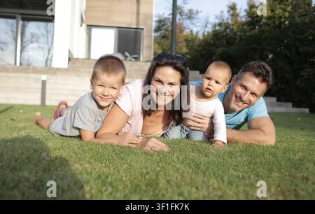 Glückliche vierköpfige Familie entspannt sich auf dem Rasen Stockfoto