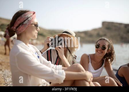 Frau macht ein Foto von ihren Freunden am Strand Stockfoto