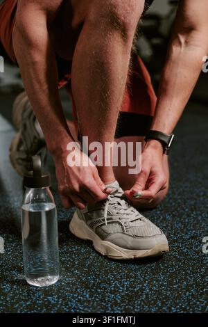 Mann bindet Laufschuh vor dem Training im Fitnessstudio Stockfoto