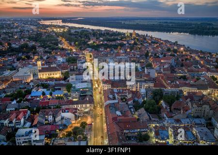 Luftbild des historischen Stadtteils Zemun in Belgrad bei Sonnenuntergang, mit der Donau, rotgedeckten Dächern, Straßenlaternen und einer Kirche in Belgrad, Ci Stockfoto