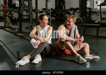 Sportlicher Mann und Frau, die sich nach dem Training im Fitnessstudio ausruhen Stockfoto