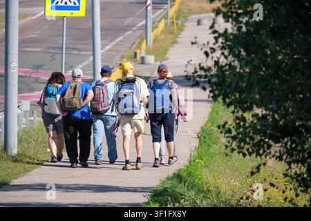 KIEW, UKRAINE, 12. Juli 2026, Eine Gruppe von Wanderern mit Rucksäcken geht entlang eines Stadtrandsteins nach einem sommerlichen Outdoor-Freizeitausflug in einem Stadtpark sind Stockfoto