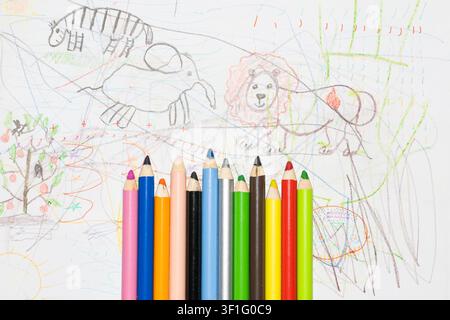 Buntstifte zum Zeichnen auf weißem Papier mit Kinderzeichnungen. Stockfoto