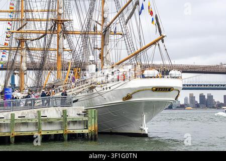 USCGC Eagle (Barque Eagle), Segelschiff der United States Coast Guard, das im South Street Seaport in Manhattan liegt, mit der Brooklyn Bridge im Hintergrund Stockfoto