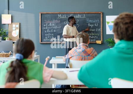 Schwarzer männlicher Lehrer erklärt eine Mathematikstunde Kindern im Klassenzimmer Stockfoto