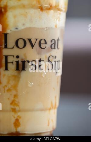 Makroaufnahme eines Plastikbechers mit Kondenswassertropfen und Text über Eiskaffee mit Karamellsoße Stockfoto