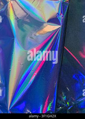 Reflektives holographisches Material, das ein lebendiges Farbspektrum einschließlich Rosa, Blau, Grün und Gelb anzeigt. Dezente Falten und Fältchen erzeugen Dynamik Stockfoto