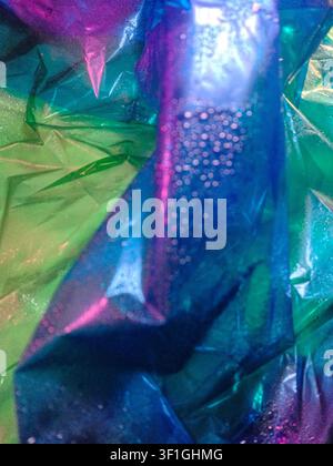 Helle, lebendige Farben von Grün und Blau aus irisierendem Material, das einen abstrakten, strukturierten Hintergrund erzeugt. Weiches Licht reflektiert von glänzenden Oberflächen, Hervorhebung Stockfoto