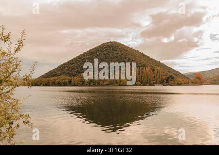 Malerische Herbstlandschaft des Lago di Piediluco in Terni, Umbrien, Italien, mit einem markanten kegelförmigen Berg, der sich auf der ruhigen Seenoberfläche spiegelt, unter Stockfoto