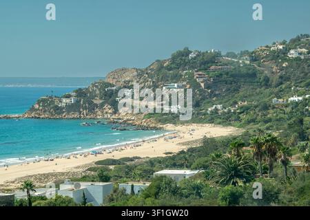 Erhöhte Panoramasicht auf einen sandigen Strand und türkisfarbenes Atlantikwasser entlang der Küste von Cadiz im Süden Spaniens. Stockfoto