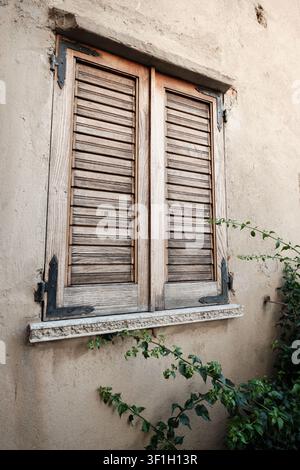Verwitterte Holzläden an einer Stuckwand in Kalabrien, Italien, ein rustikales Detail der mediterranen Architektur für Reisezwecke Stockfoto