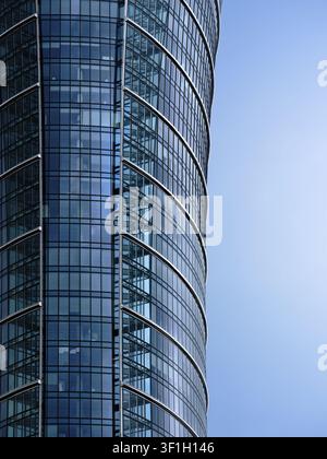 Gekrümmte Glasfassade eines modernen Büroturms, der Unternehmensarchitektur, Gewerbeimmobilien und urbane Entwicklung veranschaulicht. Stockfoto