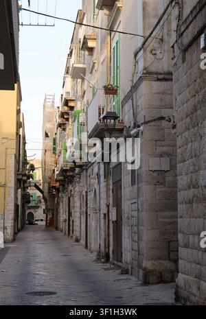 Steingebäude mit grünen Fensterläden säumen eine historische Gasse in Bari, Italien, und zeigen traditionelle europäische Architektur. Italien, Apulien, Molfetta, 21 ju Stockfoto