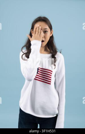 Junge Frau bedeckt das Gesicht mit der Hand und fühlt sich schüchtern oder verlegen Stockfoto