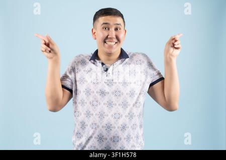 Überraschter junger Mann, der mit offenen Händen und hochgezogenen Augenbrauen nach oben schaut Stockfoto